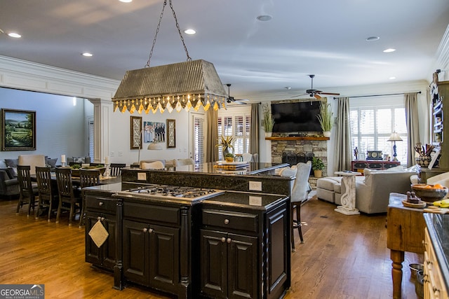 kitchen with ornamental molding, dark countertops, open floor plan, and a center island