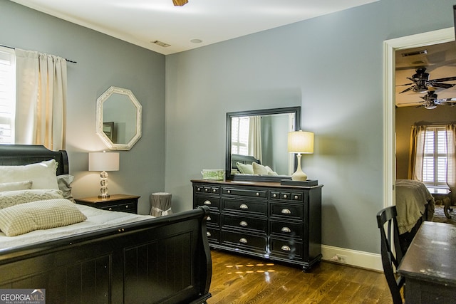 bedroom with dark wood-style floors, visible vents, and baseboards