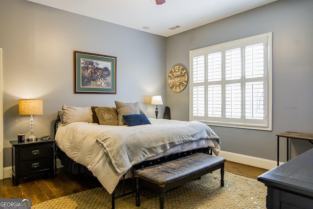 bedroom with dark wood-style floors, visible vents, and baseboards