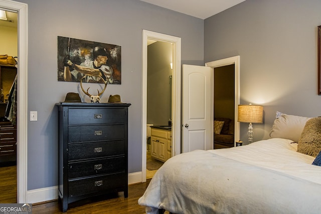 bedroom featuring ensuite bath, baseboards, and dark wood-type flooring