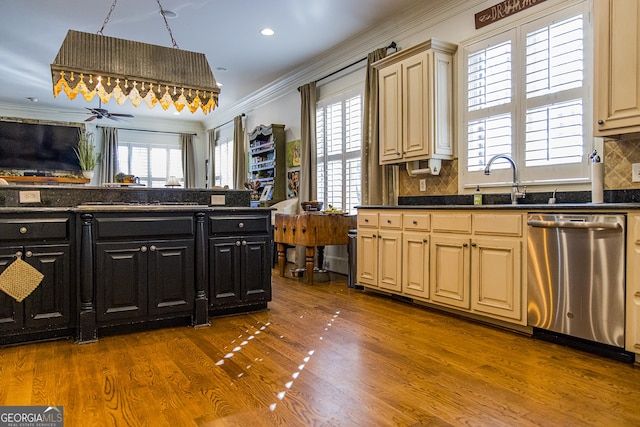 kitchen with ornamental molding, dark countertops, dishwasher, and wood finished floors