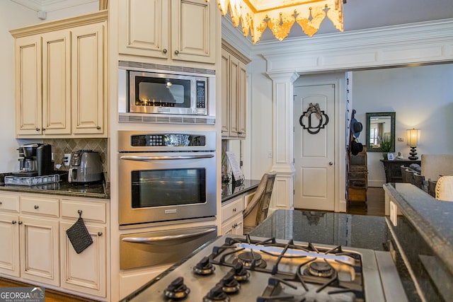 kitchen with a warming drawer, stainless steel appliances, cream cabinets, and dark stone counters