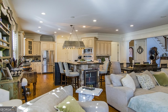 living room featuring recessed lighting, dark wood-style flooring, ornamental molding, stairway, and ornate columns