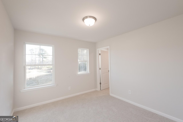 empty room featuring baseboards and light colored carpet