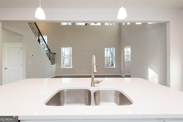 kitchen with light stone countertops, open floor plan, a sink, and decorative light fixtures