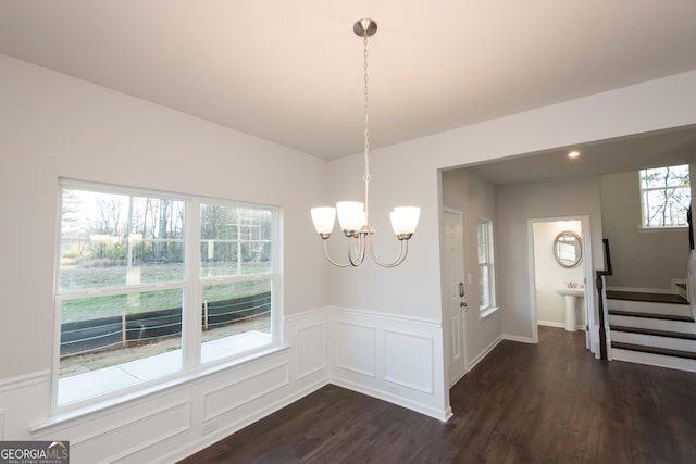 dining area with stairs, wainscoting, dark wood finished floors, and a chandelier