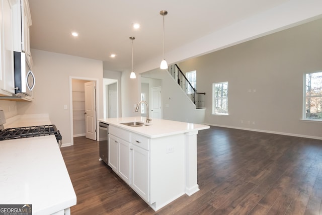 kitchen featuring light countertops, hanging light fixtures, appliances with stainless steel finishes, a sink, and an island with sink