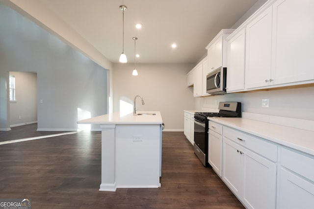 kitchen with light countertops, appliances with stainless steel finishes, a sink, and a kitchen island with sink