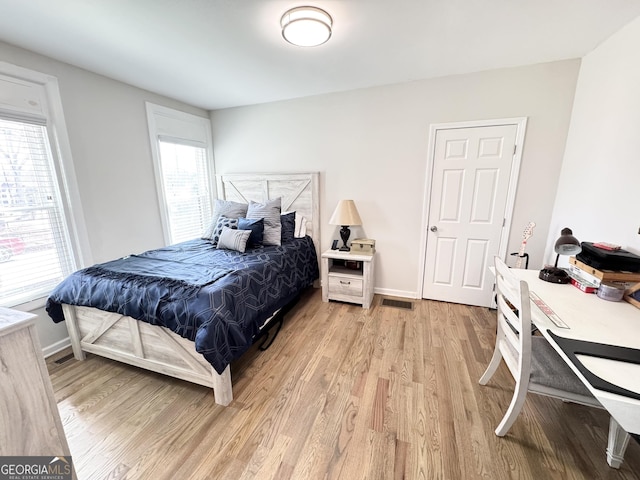 bedroom with visible vents, light wood-style flooring, and baseboards