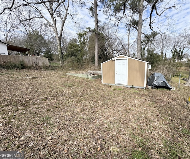 view of yard featuring a storage shed, fence, and an outdoor structure