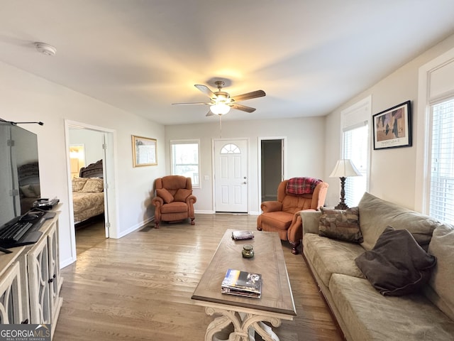 living area featuring wood finished floors, a ceiling fan, and baseboards