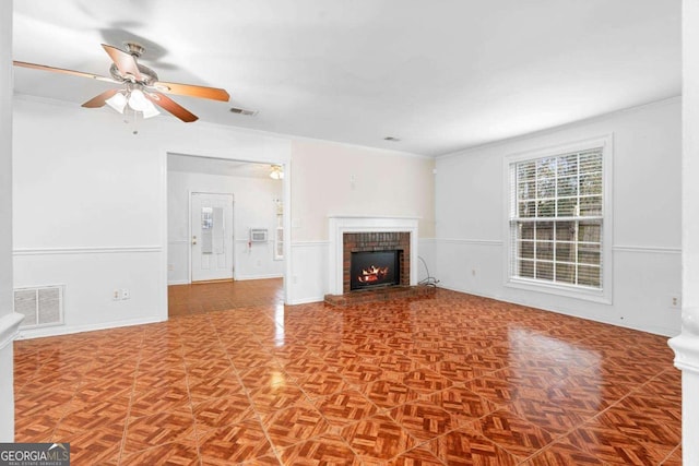 unfurnished living room with ceiling fan, ornamental molding, a fireplace, and visible vents