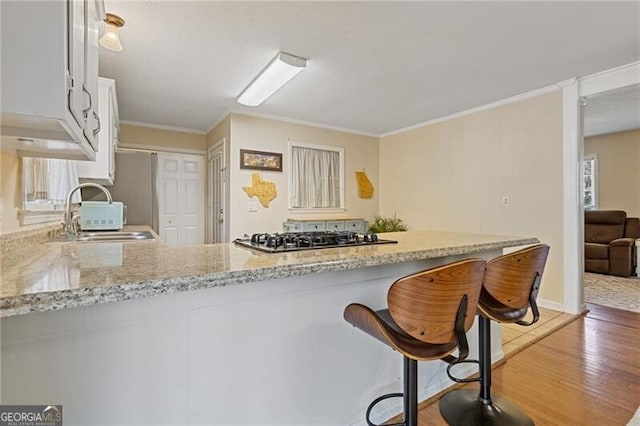 kitchen featuring a sink, light stone countertops, white cabinets, and stainless steel gas stovetop