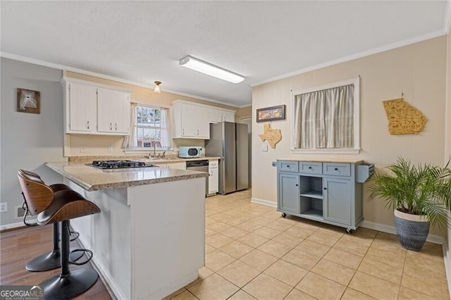 kitchen with white cabinets, appliances with stainless steel finishes, a breakfast bar, a peninsula, and crown molding