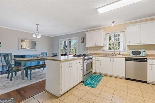 kitchen with a sink, white cabinetry, light countertops, appliances with stainless steel finishes, and decorative light fixtures