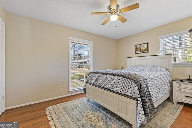 bedroom featuring multiple windows, baseboards, and wood finished floors