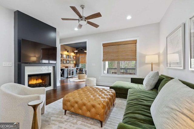 living area featuring recessed lighting, a ceiling fan, wood finished floors, and a glass covered fireplace