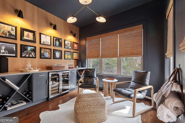 bar featuring dark wood-style flooring, beverage cooler, wooden walls, and a bar