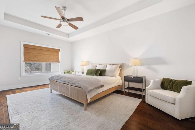 bedroom featuring visible vents, baseboards, a raised ceiling, and dark wood-style flooring