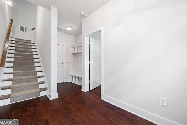 staircase with wood finished floors, visible vents, and baseboards