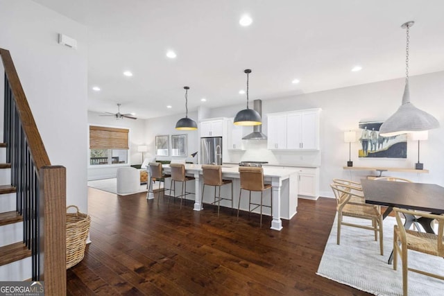 kitchen featuring light countertops, white cabinetry, a kitchen island, a kitchen breakfast bar, and stainless steel refrigerator