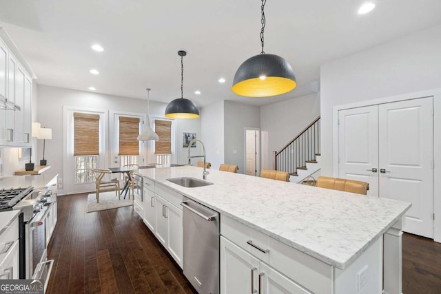 kitchen with an island with sink, appliances with stainless steel finishes, white cabinets, and a sink