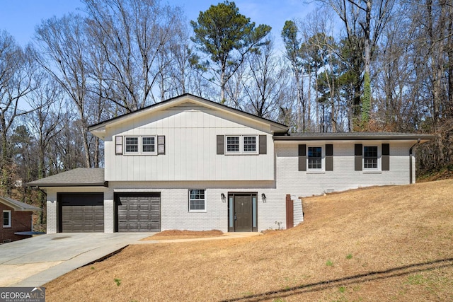 tri-level home featuring a garage, driveway, brick siding, and a front lawn