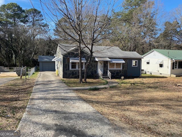 view of front of property featuring an outbuilding, stone siding, and fence