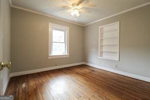 unfurnished room featuring baseboards, dark wood finished floors, and crown molding