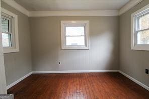 spare room featuring dark wood-style flooring and baseboards