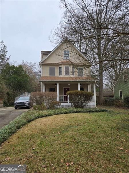 view of front facade featuring covered porch, a front lawn, and aphalt driveway