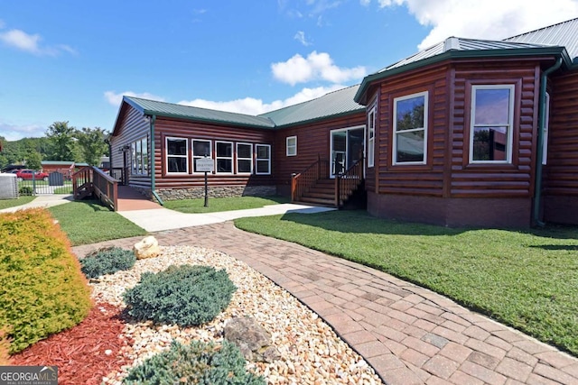 view of front facade featuring a front yard, log veneer siding, and metal roof