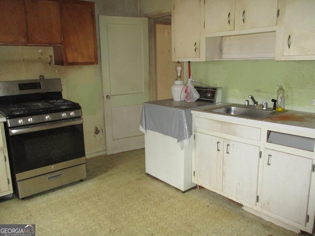 kitchen featuring light countertops, a sink, light floors, and gas range