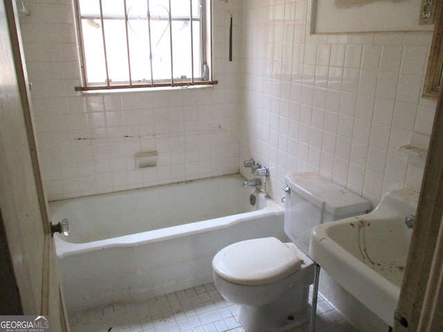 bathroom with toilet, tile patterned flooring, a bathtub, and tile walls