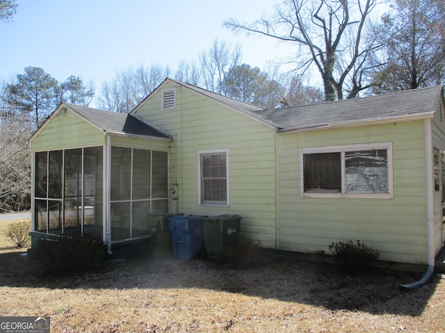 rear view of property with a sunroom and roof with shingles