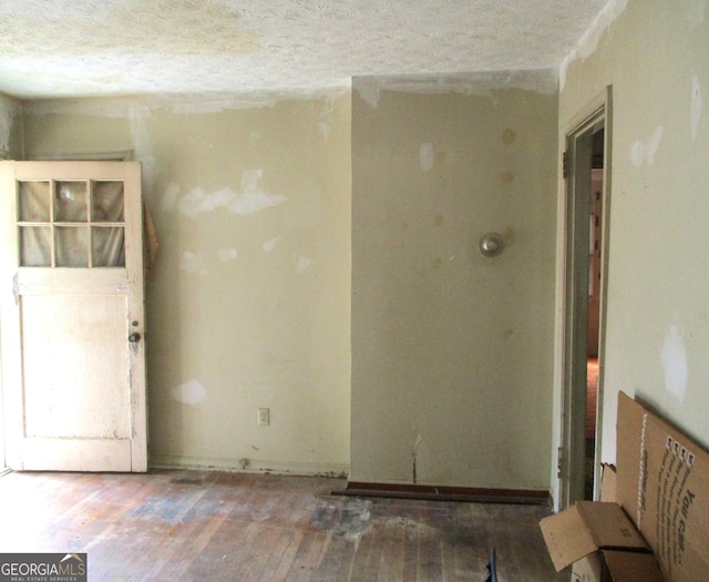 unfurnished room with hardwood / wood-style flooring and a textured ceiling