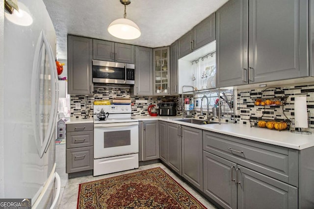 kitchen with stainless steel microwave, gray cabinets, and freestanding refrigerator