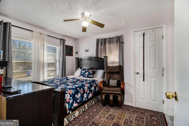 bedroom with a ceiling fan, a textured ceiling, and baseboards