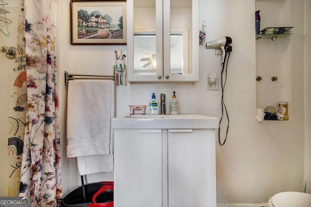 bathroom featuring toilet, a shower with curtain, baseboards, and vanity