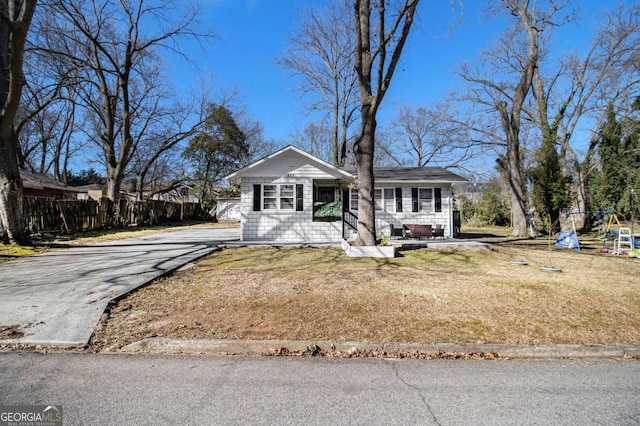 view of front of home featuring a front yard, a playground, fence, and driveway