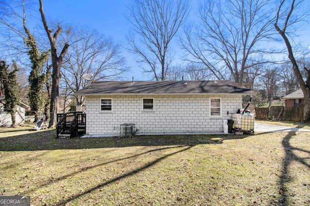 view of side of home featuring concrete block siding, a yard, and fence