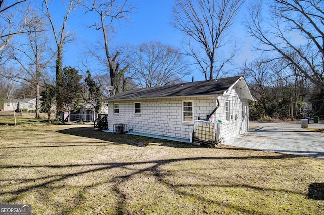 view of side of property featuring central AC unit and a lawn