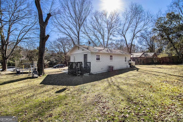 view of home's exterior with a yard, a trampoline, and fence