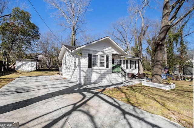 bungalow with a patio, concrete block siding, concrete driveway, a trampoline, and a front yard