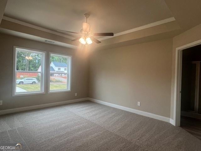 unfurnished room with visible vents, baseboards, a raised ceiling, a ceiling fan, and carpet floors