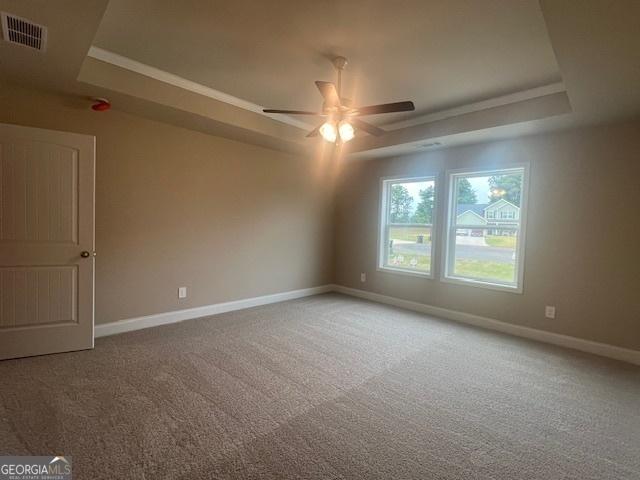 unfurnished room featuring carpet, a raised ceiling, visible vents, and baseboards