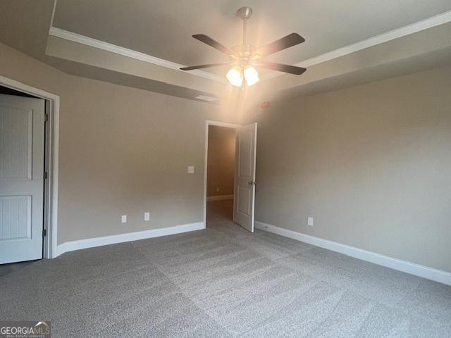 unfurnished room featuring crown molding, a raised ceiling, and baseboards