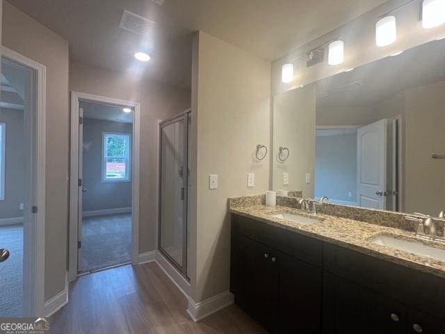 full bath featuring wood finished floors, a sink, and a shower stall