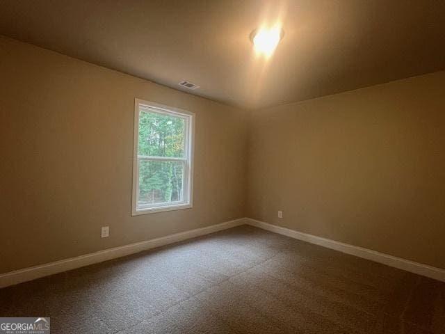 spare room with carpet flooring, visible vents, and baseboards