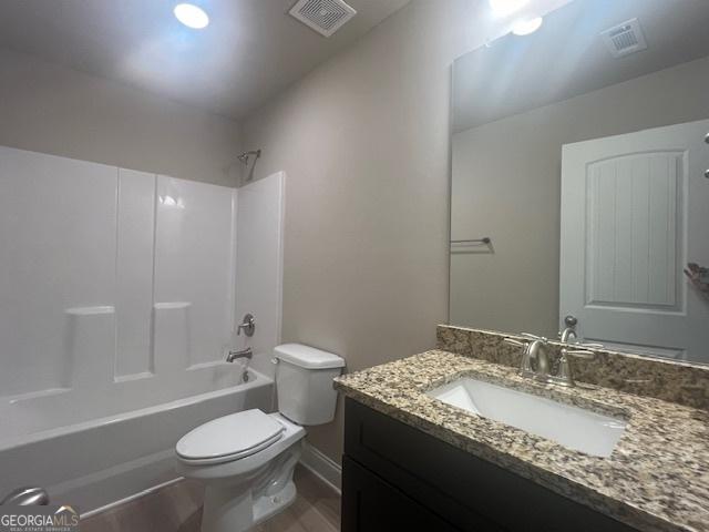 bathroom featuring toilet, vanity, visible vents, and bathing tub / shower combination